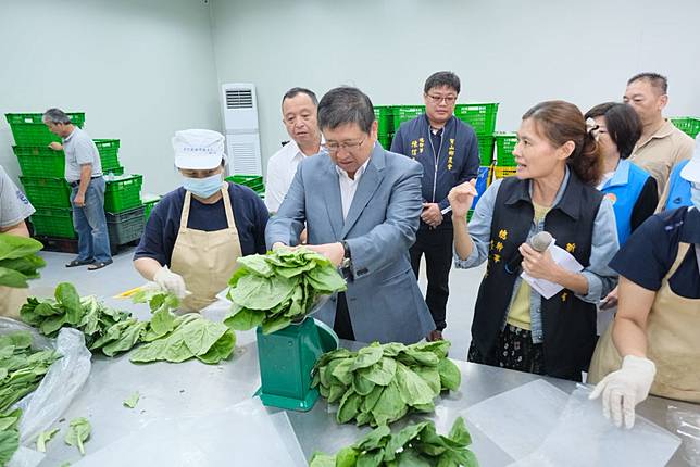 竹縣長楊文科（中）視察蔬菜分裝作業，並親自協助蔬菜分裝。（記者彭新茹攝）