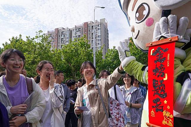 An examinee claps hands with a person dressed as a mascot sending best wishes at a national college entrance examination site in Nanjing, east China's Jiangsu Province, June 7, 2024. (Xinhua/Li Bo)