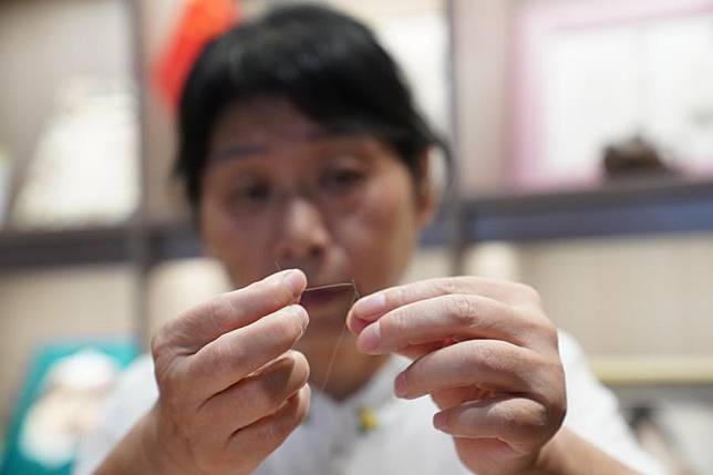 Tao Yonghong threads a hair through a needle to make Gan hair embroidery at an exhibition center for intangible cultural heritage in Nanchang, east China's Jiangxi Province, Sept. 13, 2024. (Xinhua/Zhou Mi)