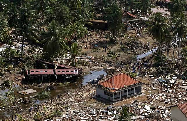 ภาพมุมสูงจากเฮลิคอปเตอร์ เผยให้เห็นชาวบ้านค้นหาผู้สูญหายตามรางรถไฟของขบวนรถไฟที่ถูกคลื่นซัดตกรางที่เทลวัตตะ ห่างจากโคลัมโบไปทางใต้ประมาณ 100 กิโลเมตร (63 ไมล์) ประเทศศรีลังกา วันที่ 29 ธันวาคม 2547 (ภาพถ่ายโดย AP Photo/Vincent Thian, ภาพเก่า)