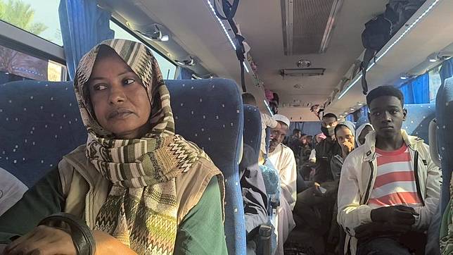 This photo taken with a mobile phone in Port Sudan shows a group of displaced individuals aboard a bus ahead of returning to Wad Madani, the capital of Gezira State in central Sudan, as part of a government program for voluntary return, Feb. 10, 2025. (Photo by Urqia Elzaki/Xinhua)