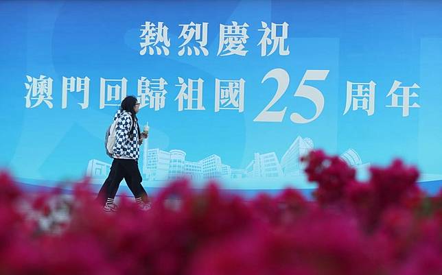 A pedestrian walks past a celebration poster in Macao, south China, Dec. 17, 2024. (Xinhua/Yao Qilin)