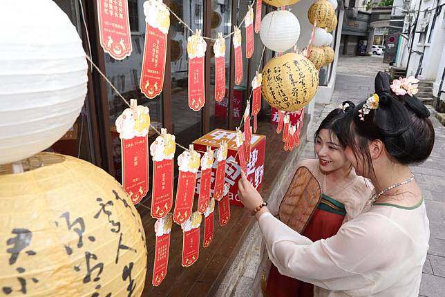 Tourists read lantern riddles in Qianyuan Town of Deqing County in Huzhou City, east China's Zhejiang Province, Sept. 17, 2024. (Photo by Ni Lifang/Xinhua)