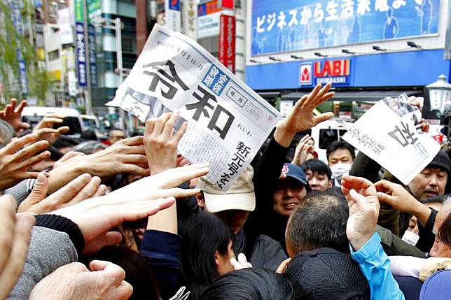 安倍政府1日終於公布新年號「令和」，日本媒體也忙著在街頭發送快報。（美聯社）