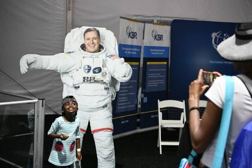 เด็กโพสต์ท่าถ่ายรูปกับเจ้าหน้าที่ขององค์การนาซ่าในชุดนักบินอวกาศ นาซ่ากำลังระดมสมองพัฒนายานลงจอดบนดวงจันทร์ Loren ELLIOTT / AFP