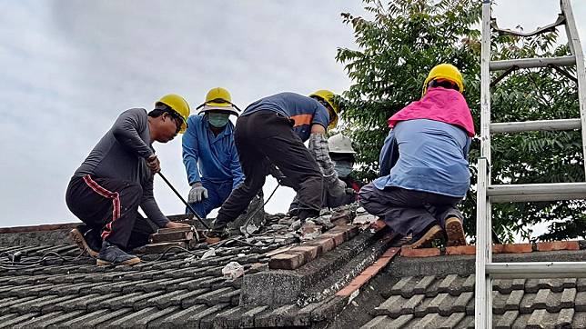 營建處陳文亮高專請專業的工班師傅上屋頂進行拆 屋瓦的工作。