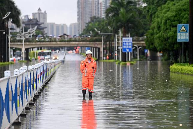 A sanitary worker stands on a waterlogged street to stop people from passing in Nanning, south China's Guangxi Zhuang Autonomous Region, May 19, 2024. (Xinhua/Lu Boan)