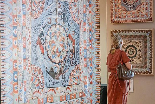 A visitor views exhibits during a Dunhuang Art Exhibition in Auckland, New Zealand, Feb. 20, 2025.(Wu Jiaxiang/Xinhua)