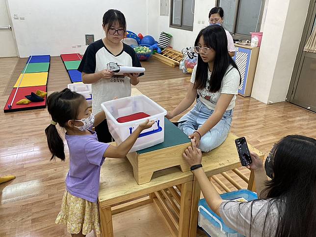 弘光科大幼保系學生測量幼童舉放箱⼦肌力。（圖：弘光科大提供）