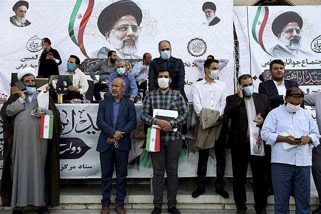 呼聲較高的伊朗保守派總統候選人萊希，表態維持核協議。圖為支持者在萊希競選海報前留影。（達志影像／美聯社）