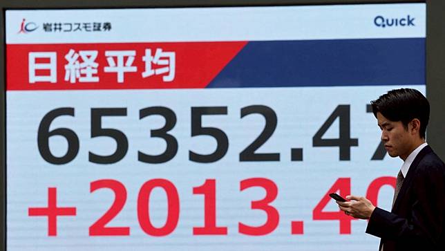 日本上班族5月25日在東京街頭經過股市指數的電子看板。路透社