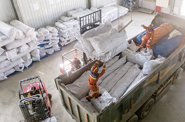 An aerial drone photo shows disaster relief support team members loading supplies onto a vehicle at a warehouse in Dingri County in Xigaze, southwest China's Xizang Autonomous Region, Jan. 15, 2025. (Xinhua/Tenzin Nyida)