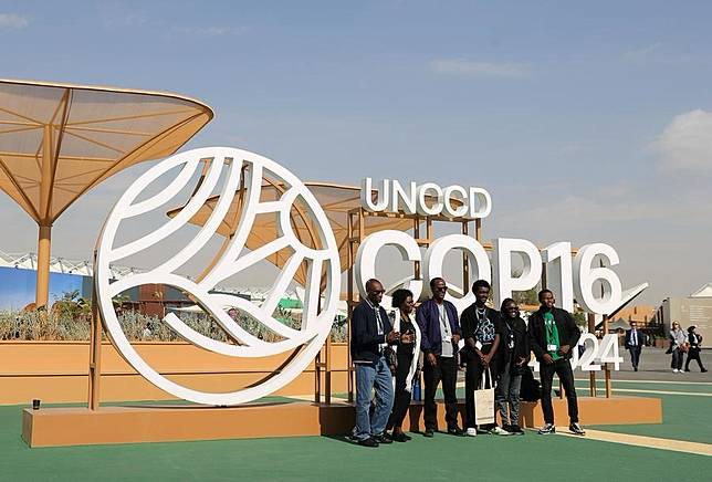 People pose for photos in front of an installation of the 16th Conference of the Parties (COP16) to the United Nations Convention to Combat Desertification (UNCCD) in Riyadh, Saudi Arabia, on Dec. 3, 2024. (Xinhua/Wang Dongzhen)