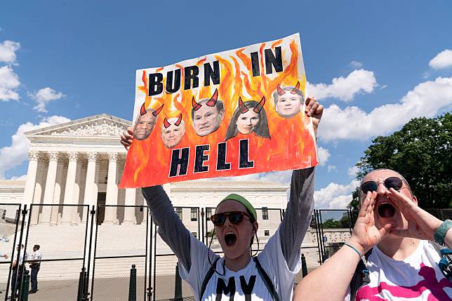 在最高法院推翻羅訴韋德案後，民眾抗議最高法院的裁決。一位抗議民眾舉起標語，上面貼著投出5張票數的大法官頭像，警告他們會在地獄中燃燒。 美聯社 / 達志影像
