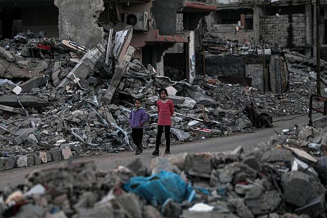 Palestinian children walk among rubble in the city of Deir al-Balah, central Gaza Strip, on Nov. 30, 2024. (Photo by Rizek Abdeljawad/Xinhua)