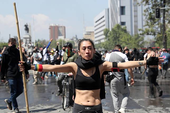 在首都聖地亞哥街頭，一名抗議民眾張開雙臂面對當局出動的水車和鎮暴警察。 路透社/達志影像