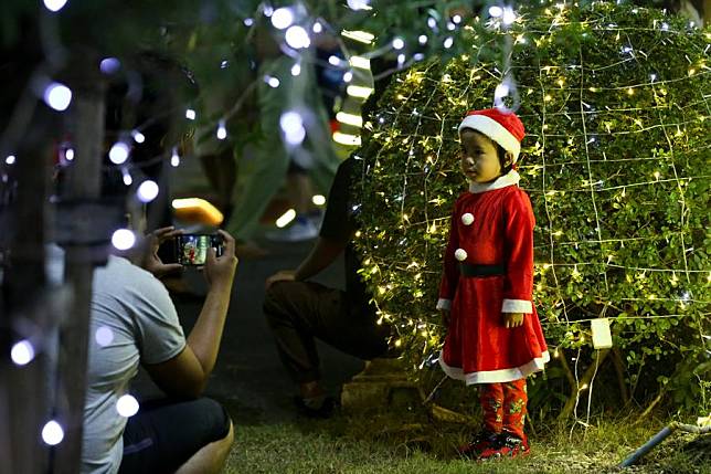 A child poses for a photo with a light installation at a church on Christmas in Yangon, Myanmar, Dec. 25, 2024. (Xinhua/Myo Kyaw Soe)