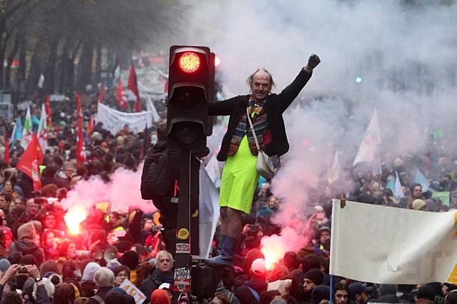在巴黎街頭，一名男子站在紅綠燈上，參加全國大罷工抗議活動。 美聯社/達志影像