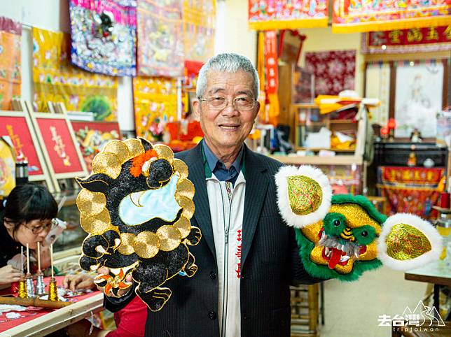 府城光彩繡莊創辦人林玉泉師傅，一手是年輕學生繡的Q版獅子，一手是繡莊出品的傳統獅子。