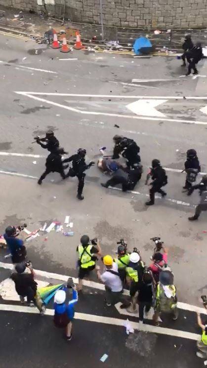 可以看到影片中的警察全副武裝圍毆1名示威民眾。(圖擷自爆廢公社)
