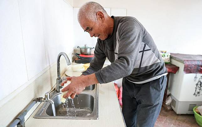 Dong Yinhua rinses vegetables at his home in Pinghe Village of Tongwei County, Dingxi City, northwest China's Gansu Province, Oct. 14, 2024. (Xinhua/Lyu Shuai)