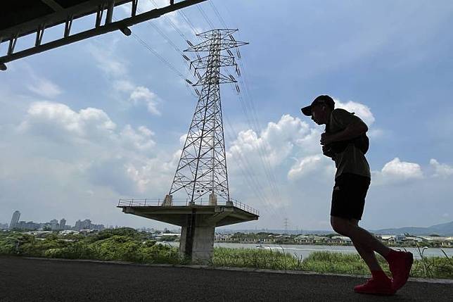 經濟部27日召開111年電價費率審議臨時會，決議平均電價調幅為8.4%，其中高壓、特高壓的產業用電大戶調漲15%。圖為民眾在台北市北投區高壓電塔旁跑步。中央社記者徐肇昌攝 111年6月27日  
