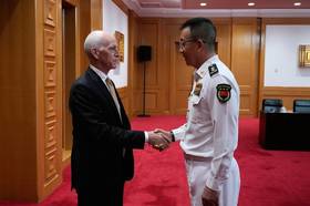 民主黨眾議員史密斯（左）率領代表團22日會晤中國防長董軍，兩人握手致意。（美聯社）