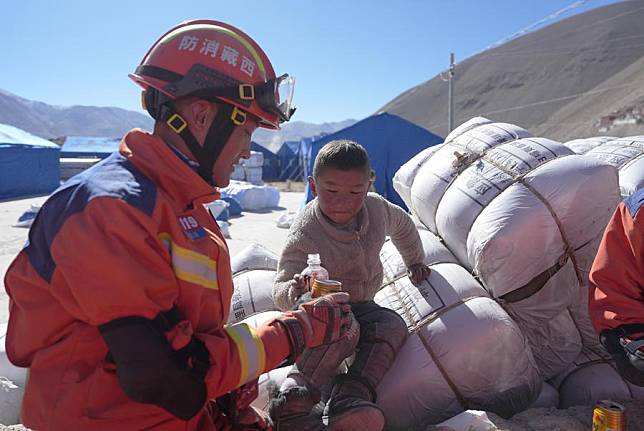 A fire rescuer interacts with a child at a relocation site in a village of Dingri County in Xigaze City, southwest China's Xizang Autonomous Region, Jan. 8, 2025. (Xinhua/Jigme Dorje)