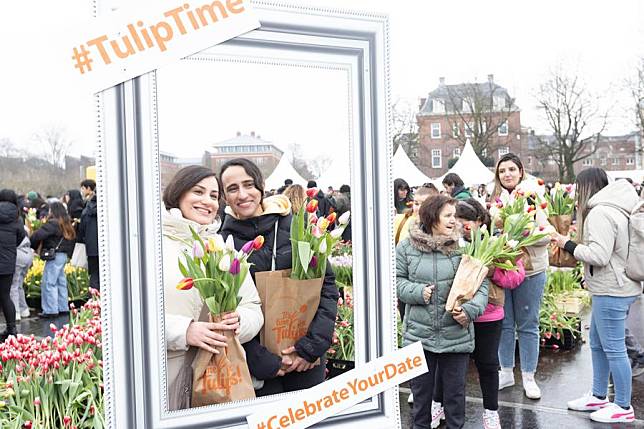 People holding bunches of tulips pose for photos at a picking garden on the Museum Square in Amsterdam, the Netherlands, Jan. 18, 2025. (Photo by Sylvia Lederer/Xinhua)