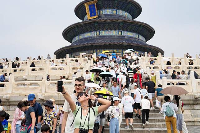 Foreign tourists pose for a photo in front of the Hall of Prayer for Good Harvests, or Qiniandian, at the Tiantan (Temple of Heaven) Park in Beijing, capital of China, July 9, 2024. (Xinhua/Ju Huanzong)