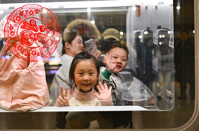 Two kids gesture aboard a train bound for Guiyang, southwest China's Guizhou Province, at Shanghai Hongqiao Railway Station in east China's Shanghai, Jan. 14, 2025. (Photo by Chen Haoming/Xinhua)