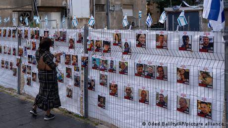 一名以色列女性在看被劫持人質的照片（2023年11月22日）