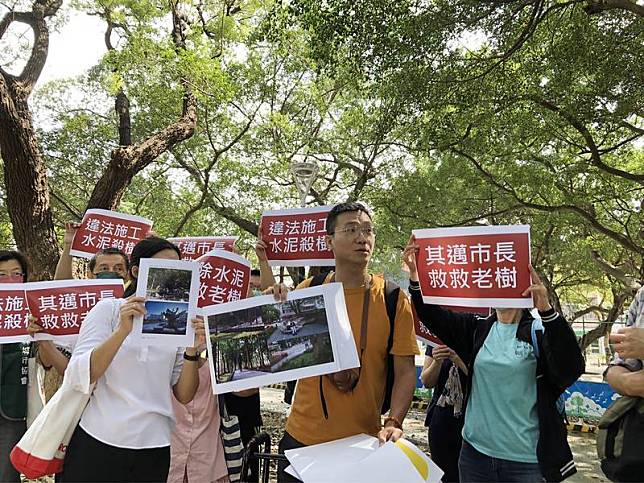 森林城市協會等護樹團體29日上午在左營三角公園高舉「違法施工、水泥殺樹」等標語，指控高雄市政府辦理左營大路人行道改建工程，造成公園10多棵老樹根系空間被灌注水泥及覆土，快要窒息死亡。 （森林城市協會提供） 中央社記者蔡孟妤傳真 111年9月29日  
