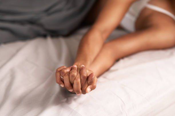 情侶在床上手牽手。(圖/取自istockphoto)