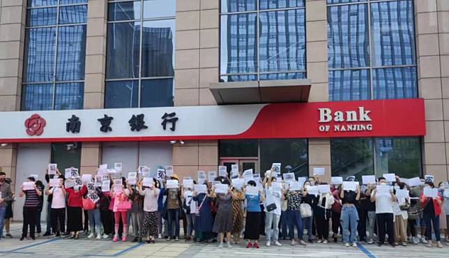 儲戶在銀行外高舉「冤」字牌抗議。   圖: 翻攝自 用戶7738534297 微博
