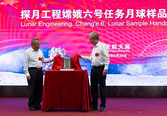 Zhang Kejian (L), head of the China National Space Administration (CNSA), and Ding Chibiao, vice president of the Chinese Academy of Sciences (CAS), unveil the sample container during the Chang'e-6 lunar sample handover ceremony in Beijing, capital of China, June 28, 2024. (Xinhua/Jin Liwang)