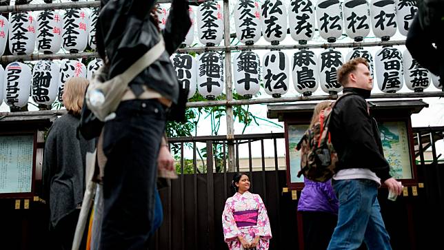 日本黃金週期間，不少日本人選擇出遊旅行，但卻也發生一些讓飯店業者頭疼的事情。圖為名身穿日本傳統和服的遊客站在購物街。美聯社