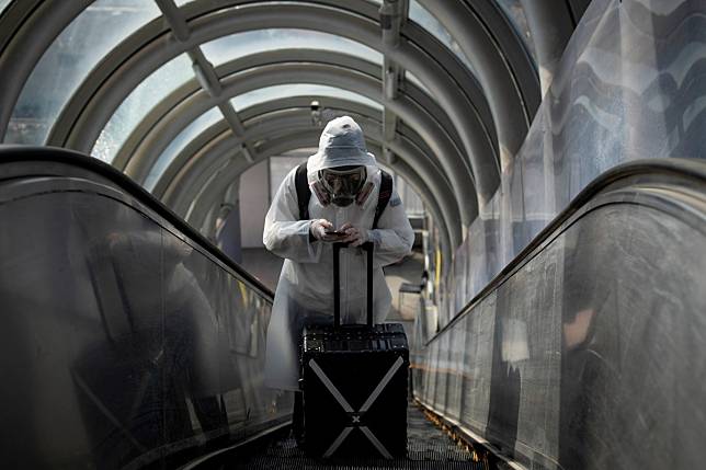 A traveller wearing protective clothing and a mask goes in Beijing. Photo: Reuters