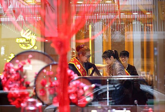 A customer tries gold jewelry at a store during the Mid-Autumn Festival holiday in Danzhai County, southwest China's Guizhou Province, Sept. 11, 2022. (Photo by Huang Xiaohai/Xinhua)