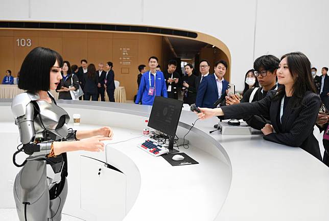 Journalists interact with a bionic humanoid robot at the Zhongguancun International Innovation Center, venue for the 2024 Zhongguancun Forum (ZGC Forum), in Beijing, capital of China, April 24, 2024. (Xinhua/Chen Zhonghao)