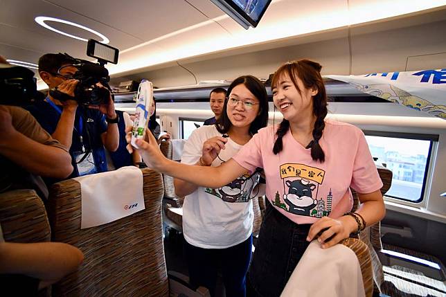 Two passengers from Taiwan speak with their family in a video chat while taking the Fuxing bullet train G9801 on the Fuzhou-Xiamen-Zhangzhou high-speed railway in southeast China's Fujian Province, Sept. 28, 2023. (Xinhua/Jiang Kehong)