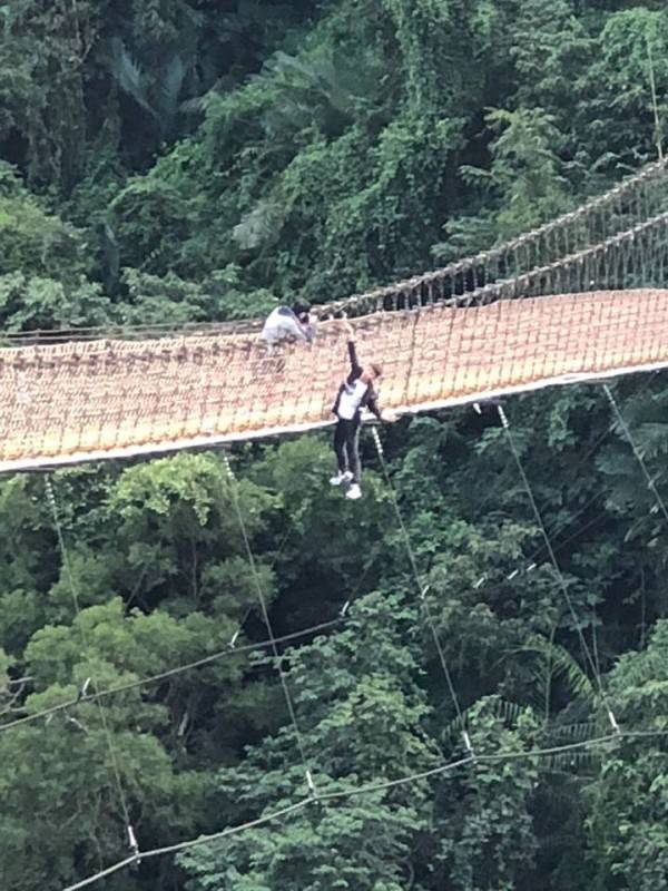 一名年輕男子為了拍照，竟只用一隻手抓住吊橋護繩，整個身體翻出吊橋外「懸掛」在橋上。(圖擷自爆料公社)
