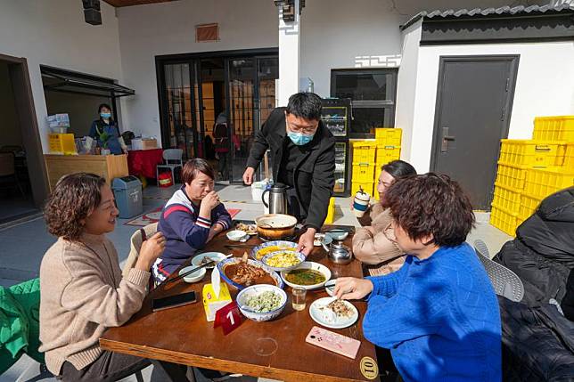 Liu Yuelong (3rd L), an agritainment owner, serves the table in Shushan Village in Tong'an Town of Suzhou City, east China's Jiangsu Province, Jan. 11, 2024. In recent years, Tong'an Town has scaled up efforts to boost local tourism. The town has renovated and upgraded old houses in the villages to develop entertainment clusters, drawing more young talents to jump on the entrepreneurship bandwagon to start their own businesses there. (Xinhua/Li Bo)