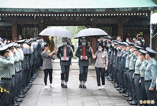 三軍儀隊人員捧著烈士牌位進入忠烈祠，家屬全程撐傘護送。(記者謝武雄攝)