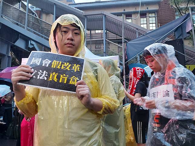 雨中在議場外舉標語抗議的民眾。攝影：陳昭宏