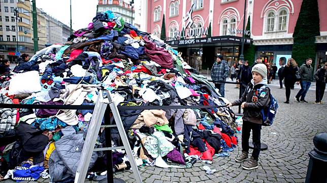 A boy stands by a pile of clothing created to raise awareness about the issue of textile waste in Prague, the Czech Republic, on Nov. 12, 2024. (Photo by Dana Kesnerova/Xinhua)