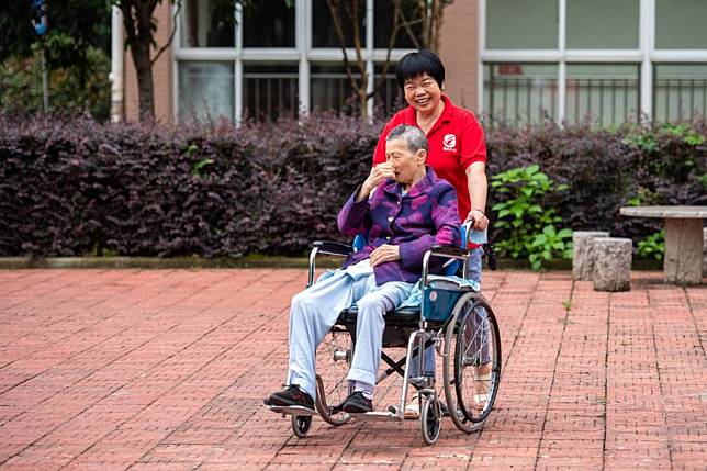 A staff member takes care of a senior resident in a wheelchair at a social welfare center in Hanshou County of Changde City, central China's Hunan Province, June 20, 2023. (Xinhua/Chen Sihan)