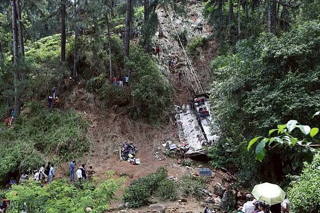 Onlookers watch as rescue workers search the debris at the site of a bus accident near the town of Kotmale, Sri Lanka Sunday, May 11, 2025. (AP Photo)