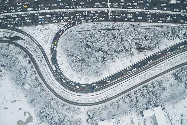 An aerial drone photo taken on Jan. 24, 2024, shows vehicles running on the road during snowy weather in Changsha, central China's Hunan Province, Jan. 22, 2024. (Xinhua/Chen Sihan)