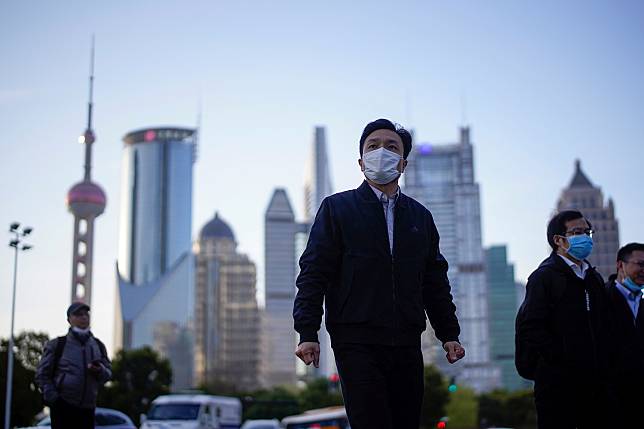 FILE PHOTO: People wear protective face masks, following an outbreak of the novel coronavirus disease (COVID-19), at Lujiazui financial district in Shanghai